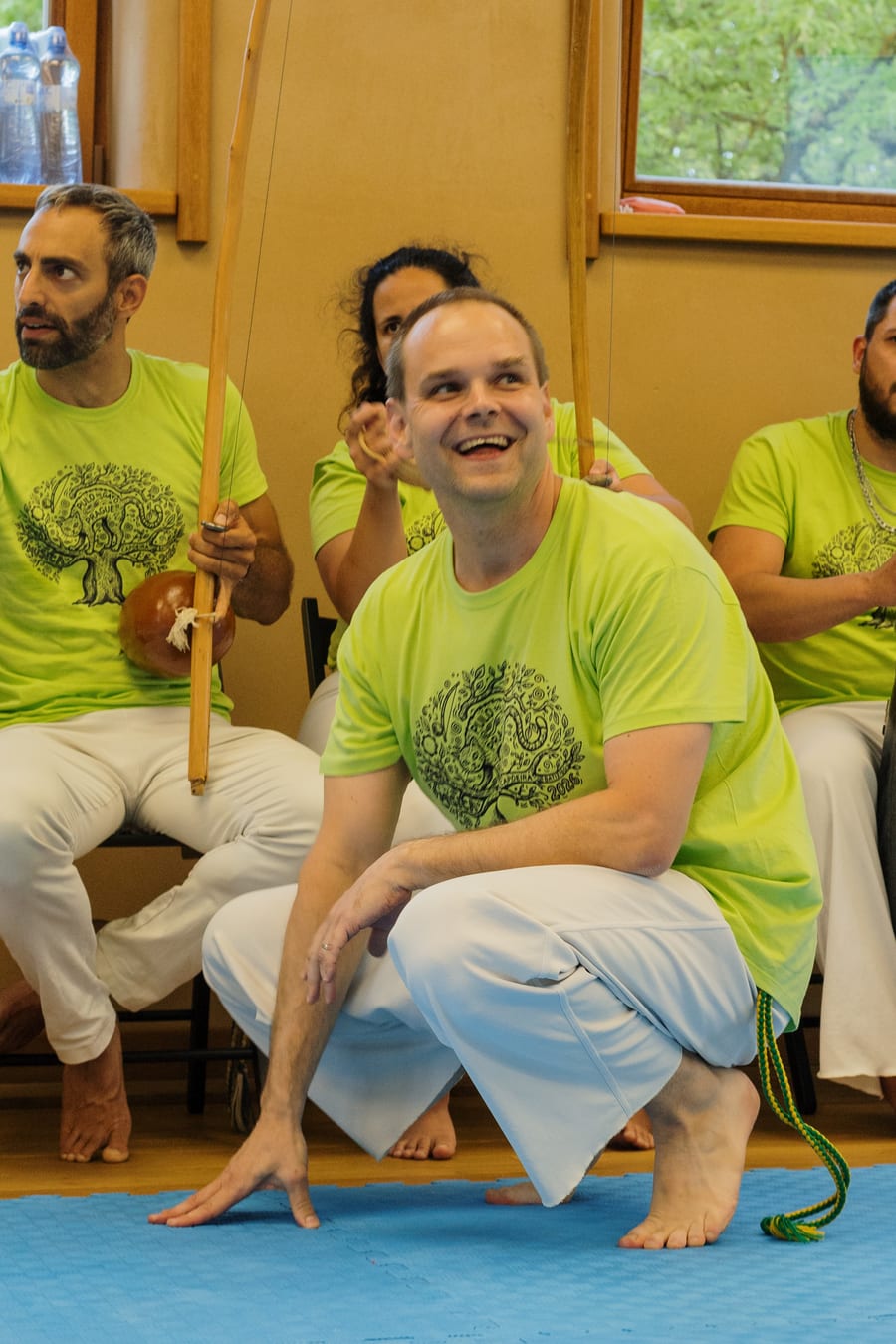 Usmívající se capoeirista v podřepu uprostřed kruhu